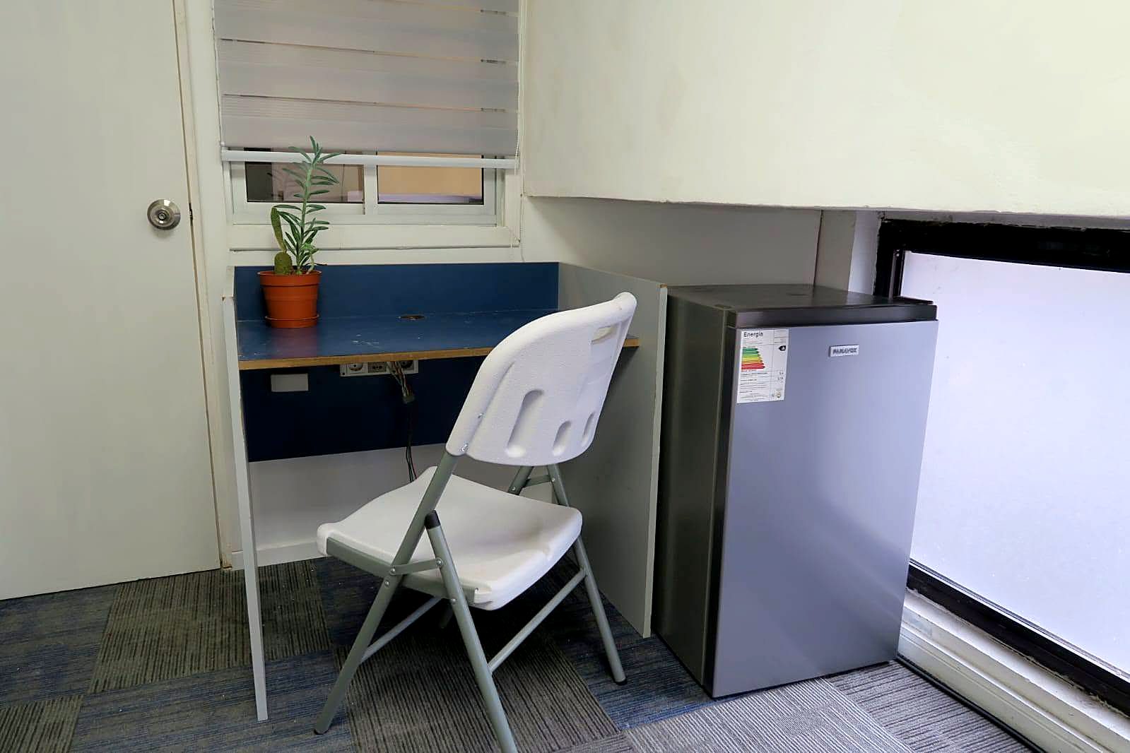 Escritorio con silla y frigobar dentro de la habitación