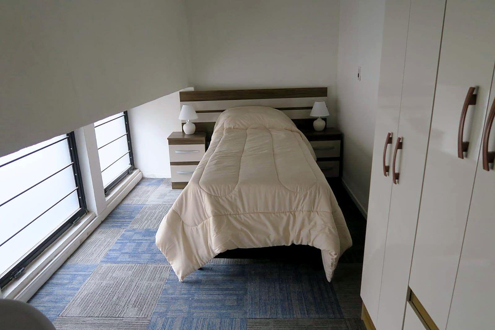 Habitación con cama individual junto a ventanales