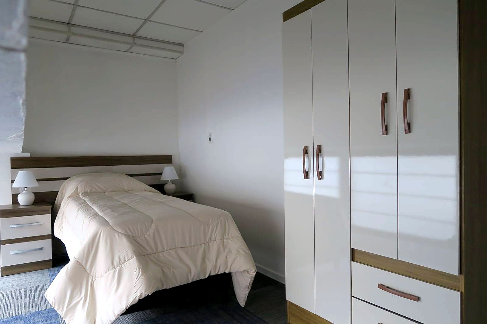 Habitación con cama individual y placard blanco con detalles en madera