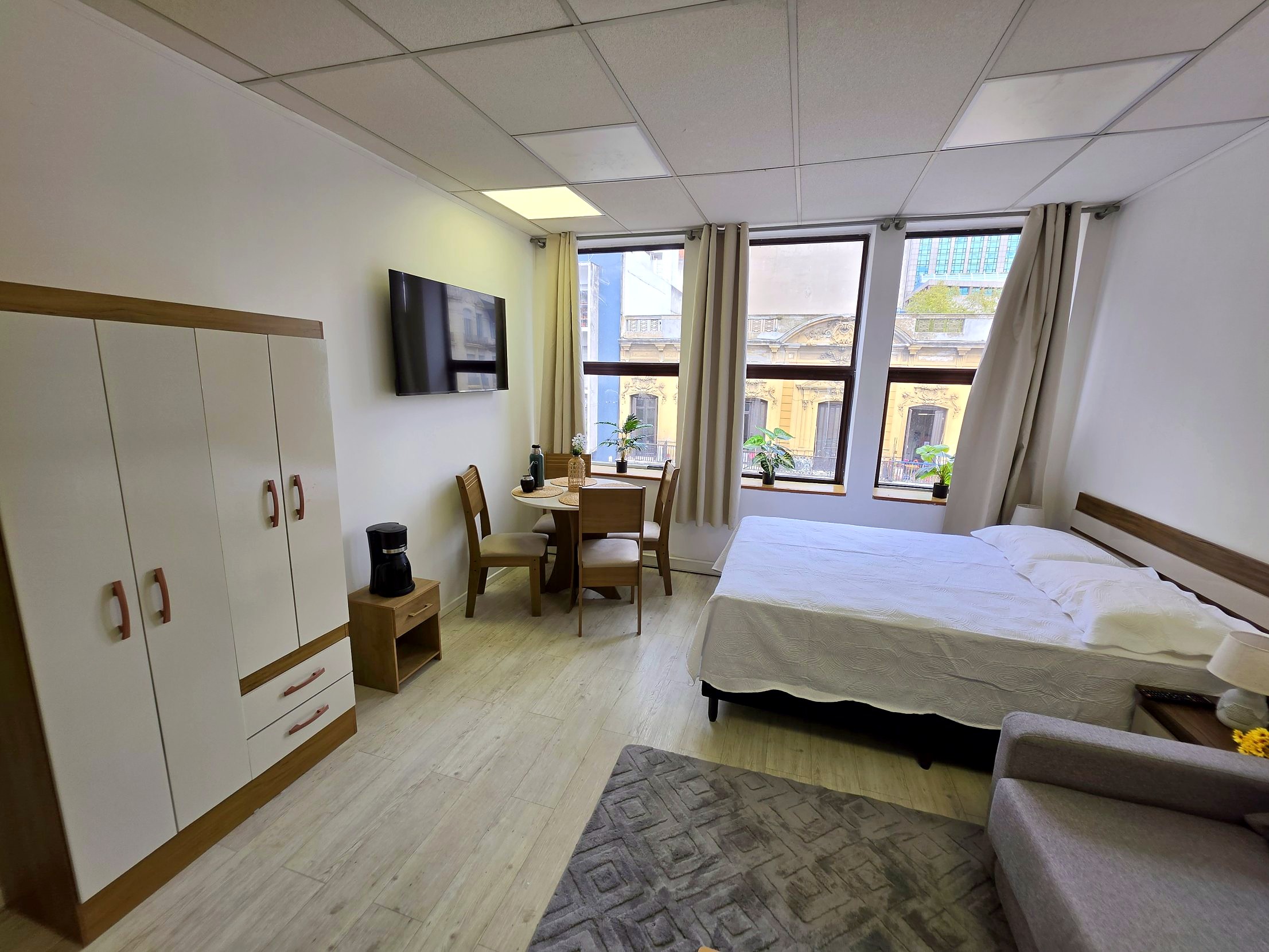 Estudio privado con cama doble, mesa de comedor y grandes ventanales