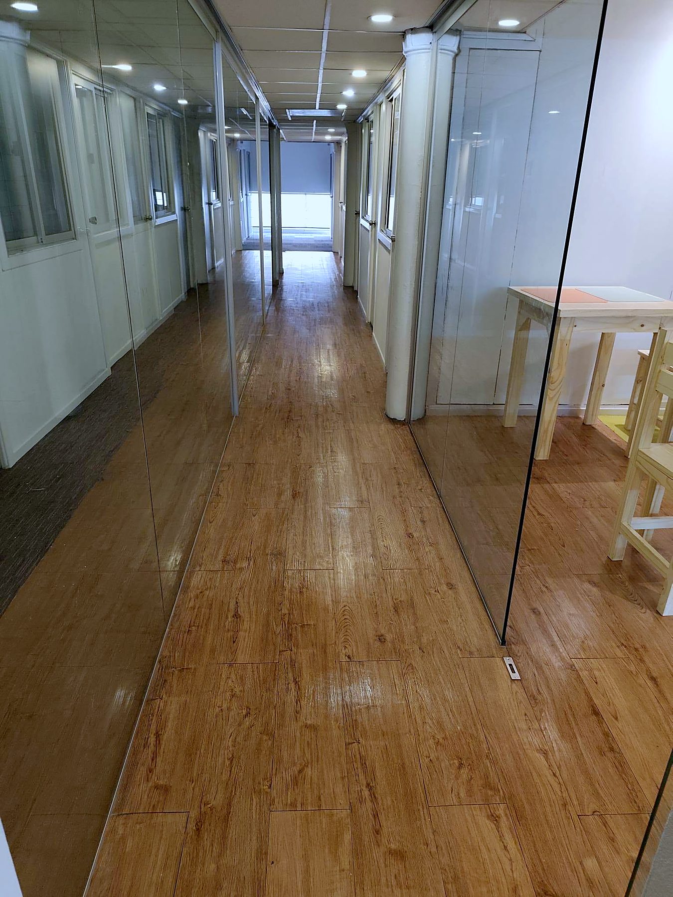 Pasillo con piso de madera y divisiones de vidrio