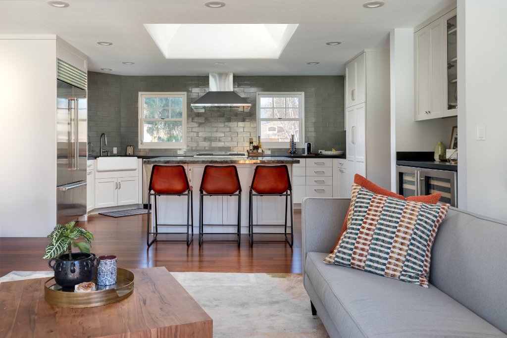 Los Altos kitchen and dining with white shaker cabinetry, black granite countertops, a sage-green subway-tile backsplash, a green marble island, and a stacked-stone accent wall.