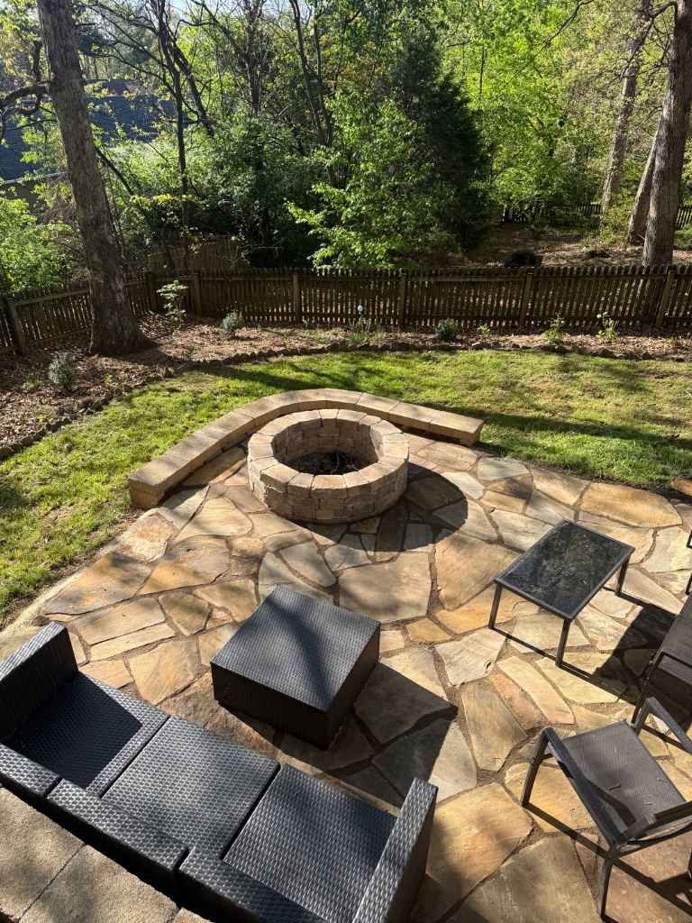 Custom flagstone patio with stone fire pit and outdoor seating area built by Grateful Grounds in Knoxville TN
