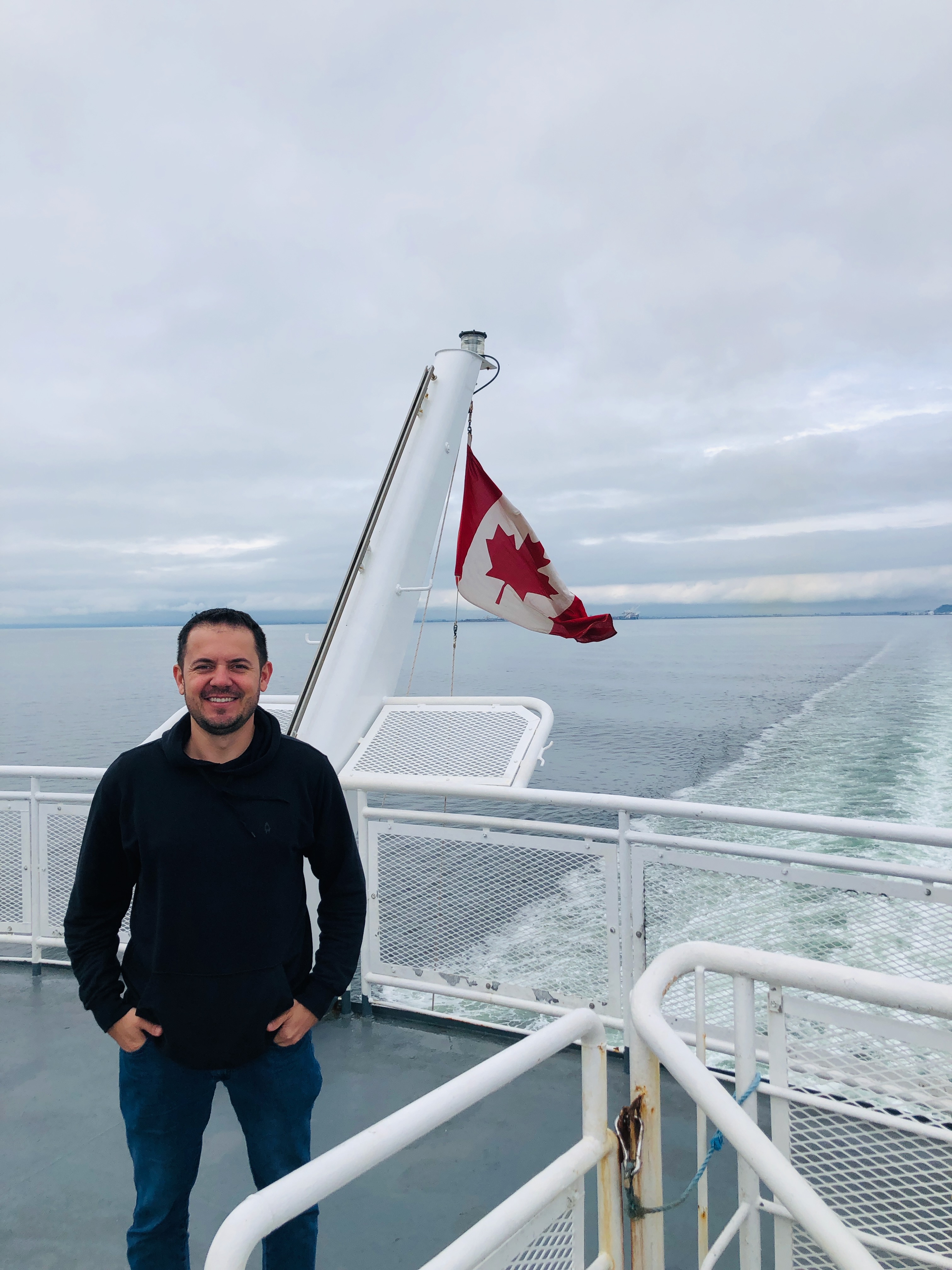 Bruno Santiago, marketing strategist, on a BC ferry with a Canadian flag behind him