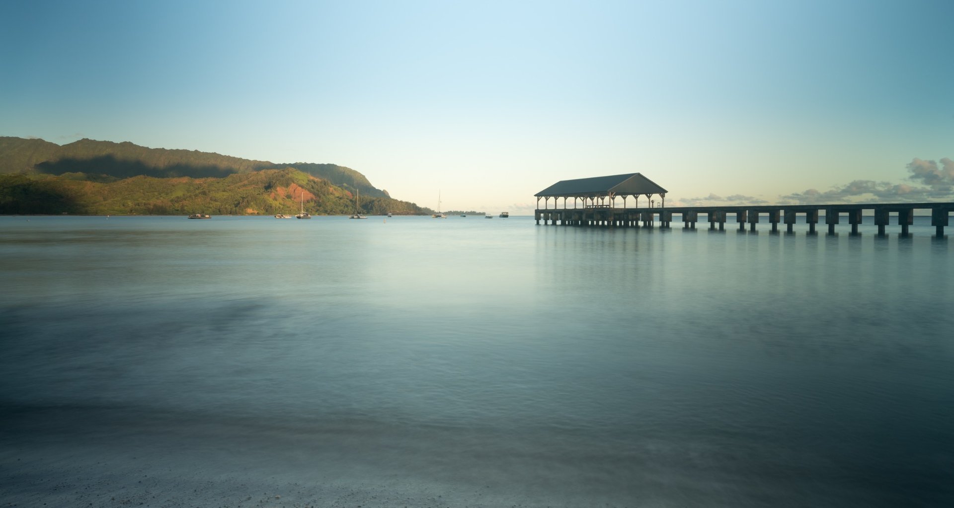 Hanalei Pier extending over calm water on Kauaʻi's North Shore.