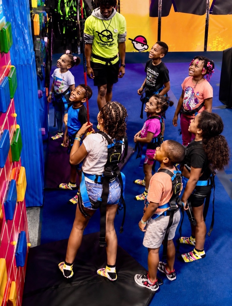 Urban Air Adventure Park Rock Wall Children at Urban Air Adventure Park wearing safety harnesses preparing to climb the colorful rock wall during an Insight Kidz Care field trip