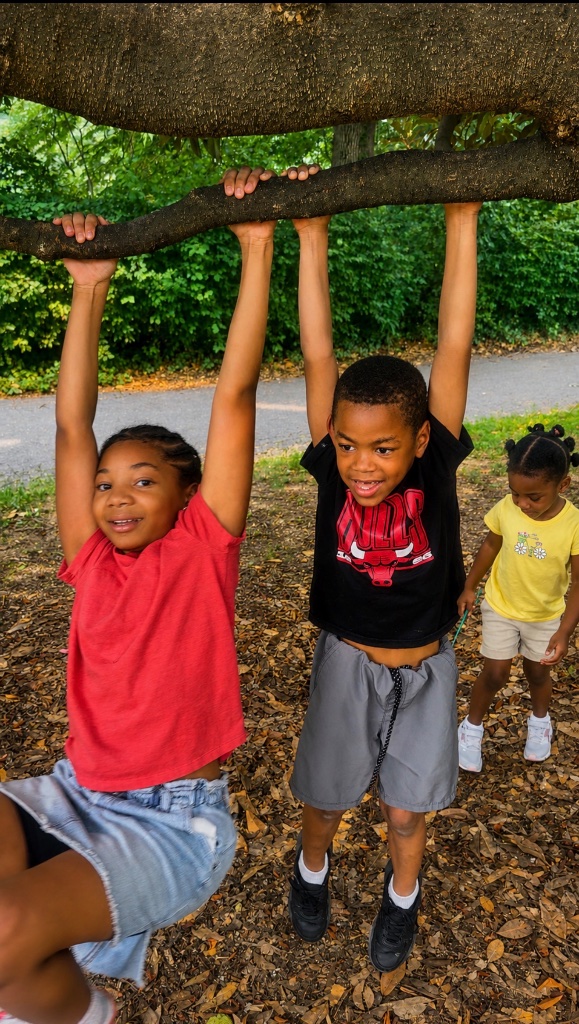 Outdoor Adventure & Gross Motor Play Children climbing and hanging from a tree branch during supervised outdoor play at Insight Kidz Care in Baltimore.