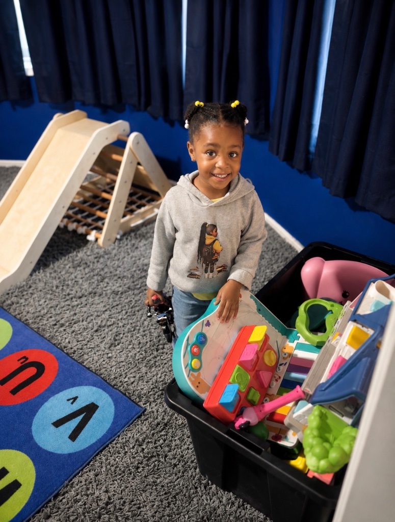 Free Play with Activity Center Child smiling with a toddler toy activity center during free play and exploration at Insight Kidz Care licensed child care in Baltimore