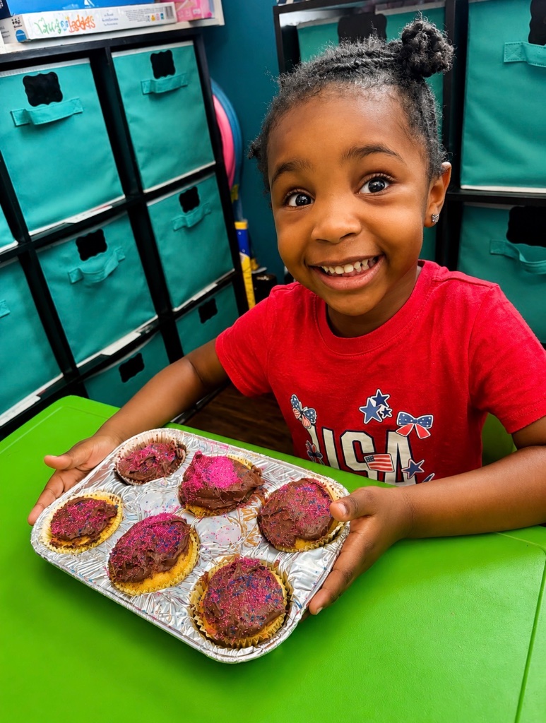Child proudly displaying a tray of homemade chocolate frosted cupcakes she made during cooking class at Insight Kidz Care Baltimore