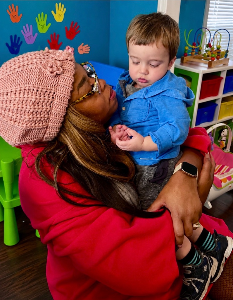 Comforting Hug from Teacher Teacher lovingly holding and comforting a young toddler in a colorful classroom at Insight Kidz Care licensed child care in Baltimore