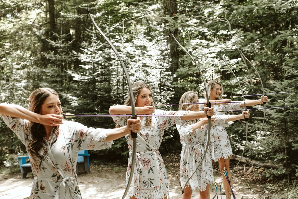 Bridesmaids doing archery in the forest