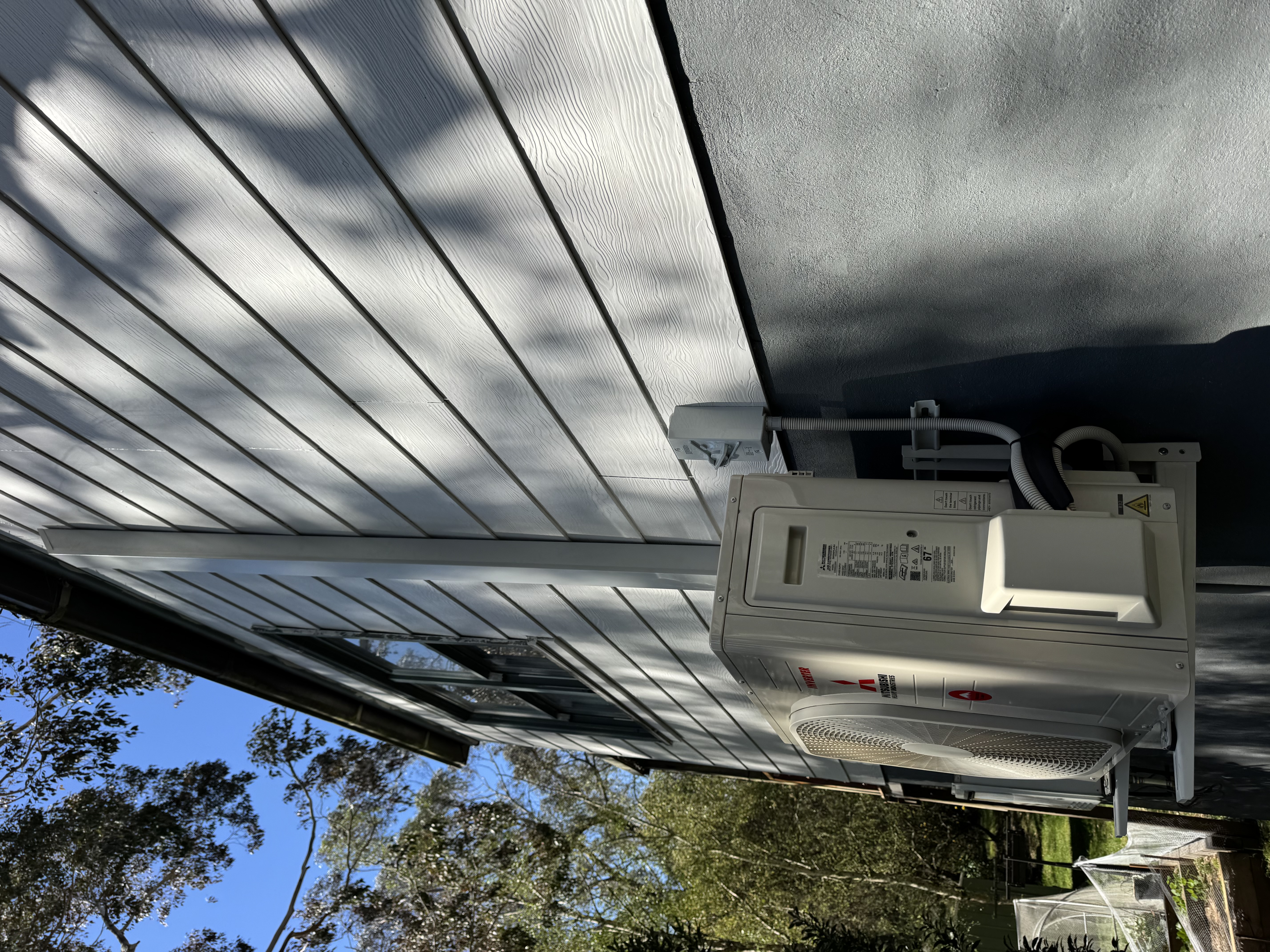 Outdoor air conditioning unit mounted on the side of a weatherboard home