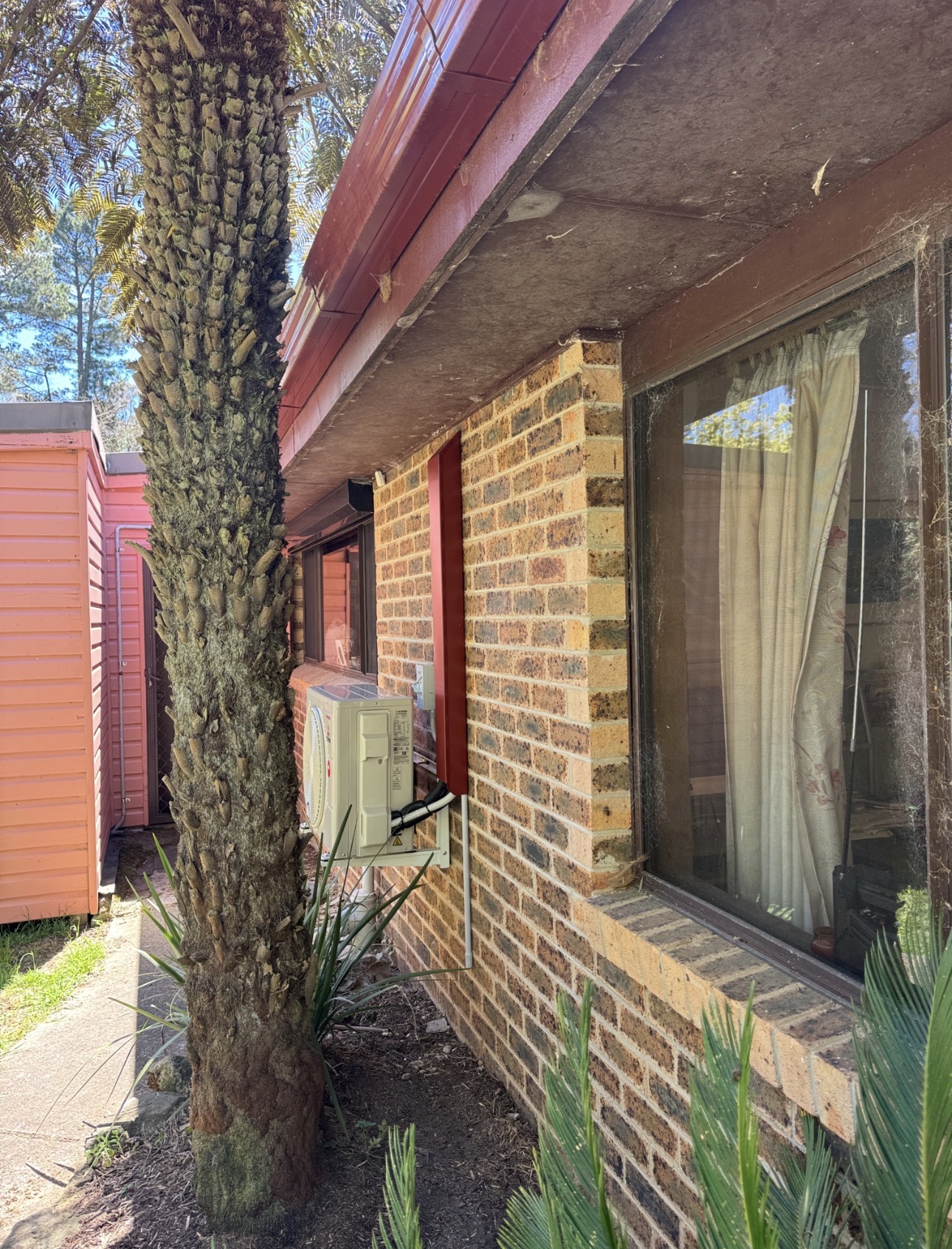 New outdoor air conditioning unit on wall brackets beside a brick home in Medlow Bath