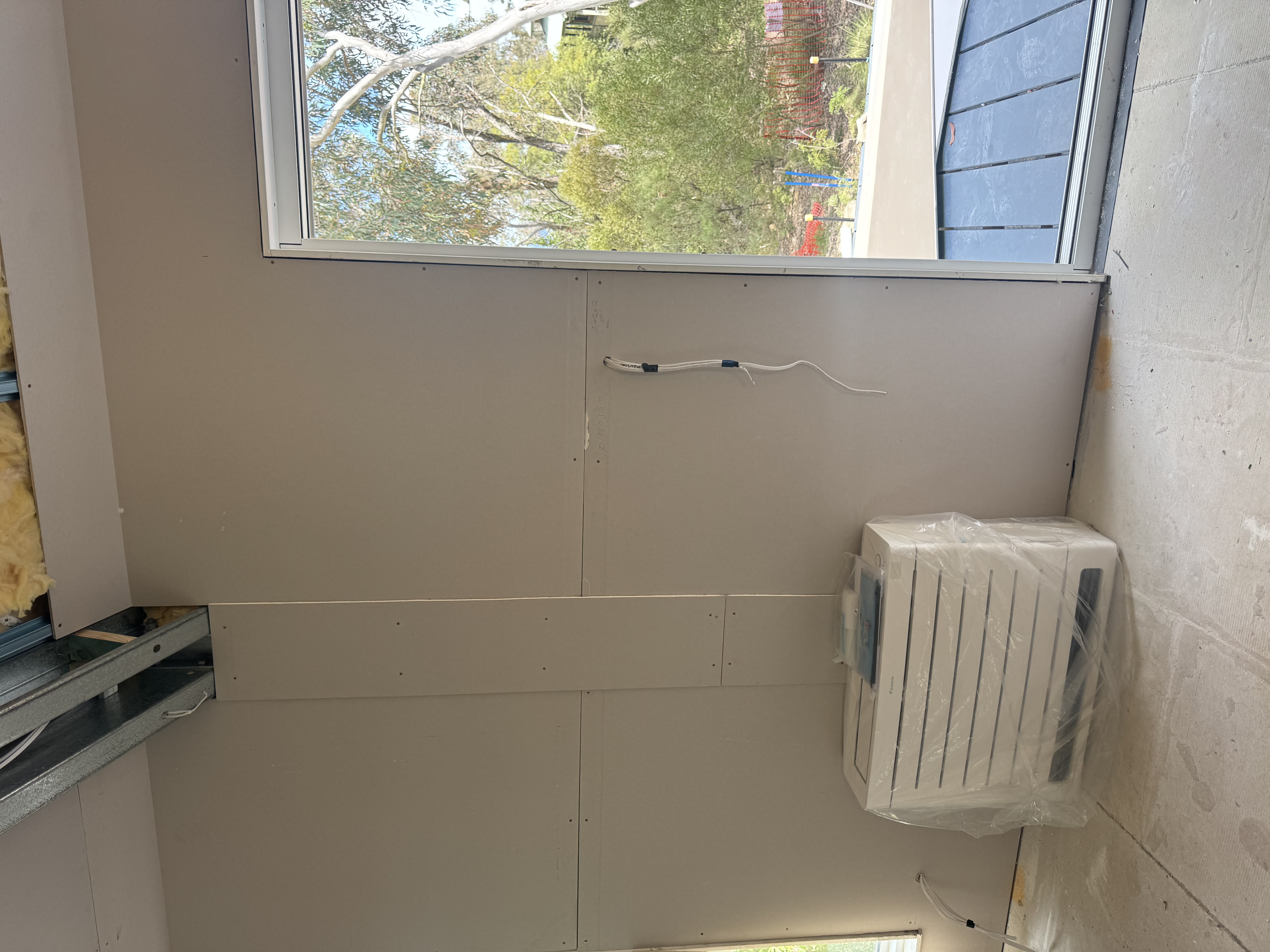 Floor-console air conditioner covered in protective wrapping beside a glazed door at Mt Victoria