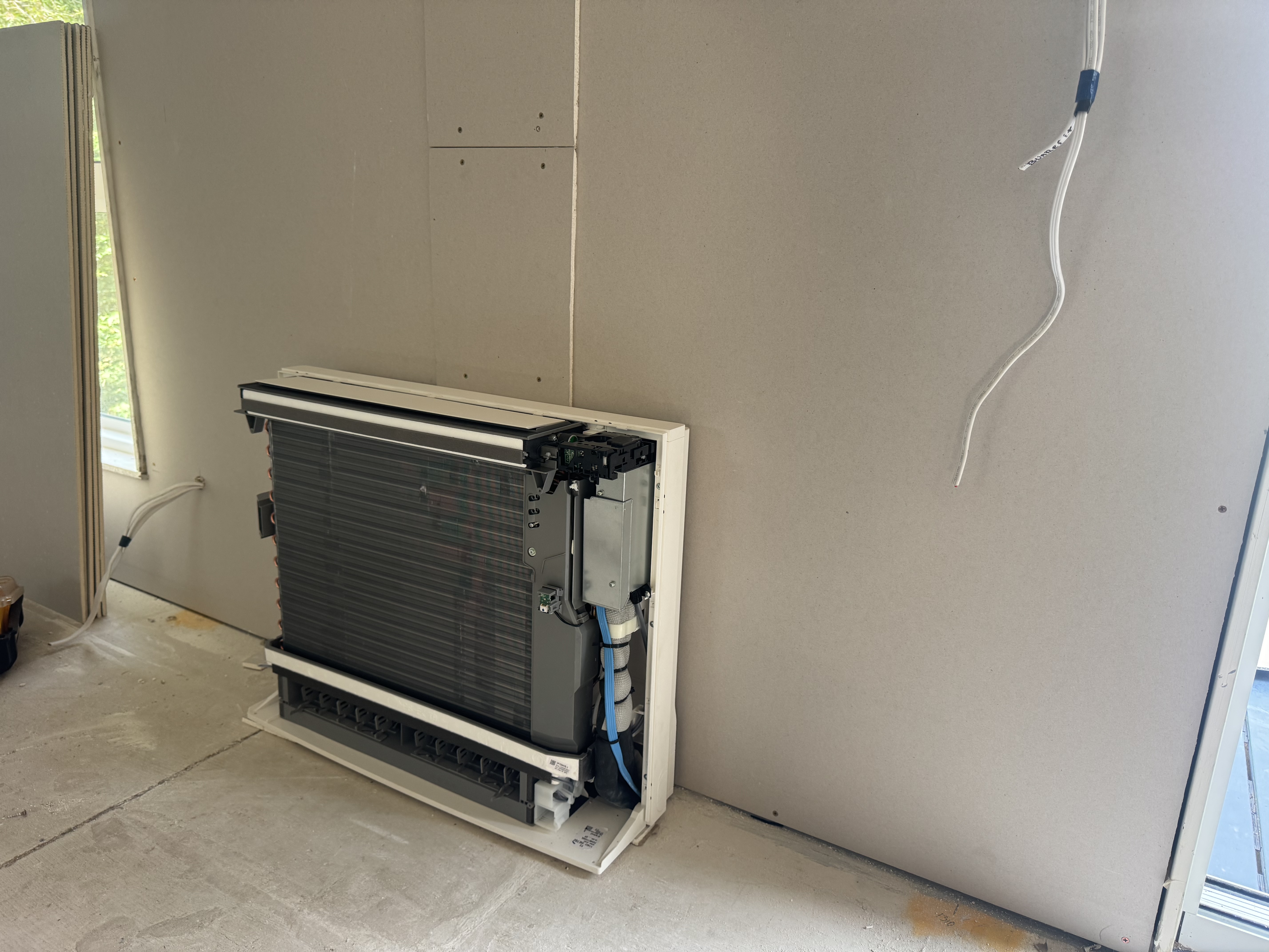 Floor-console air conditioner with its front cover removed during installation at Mt Victoria
