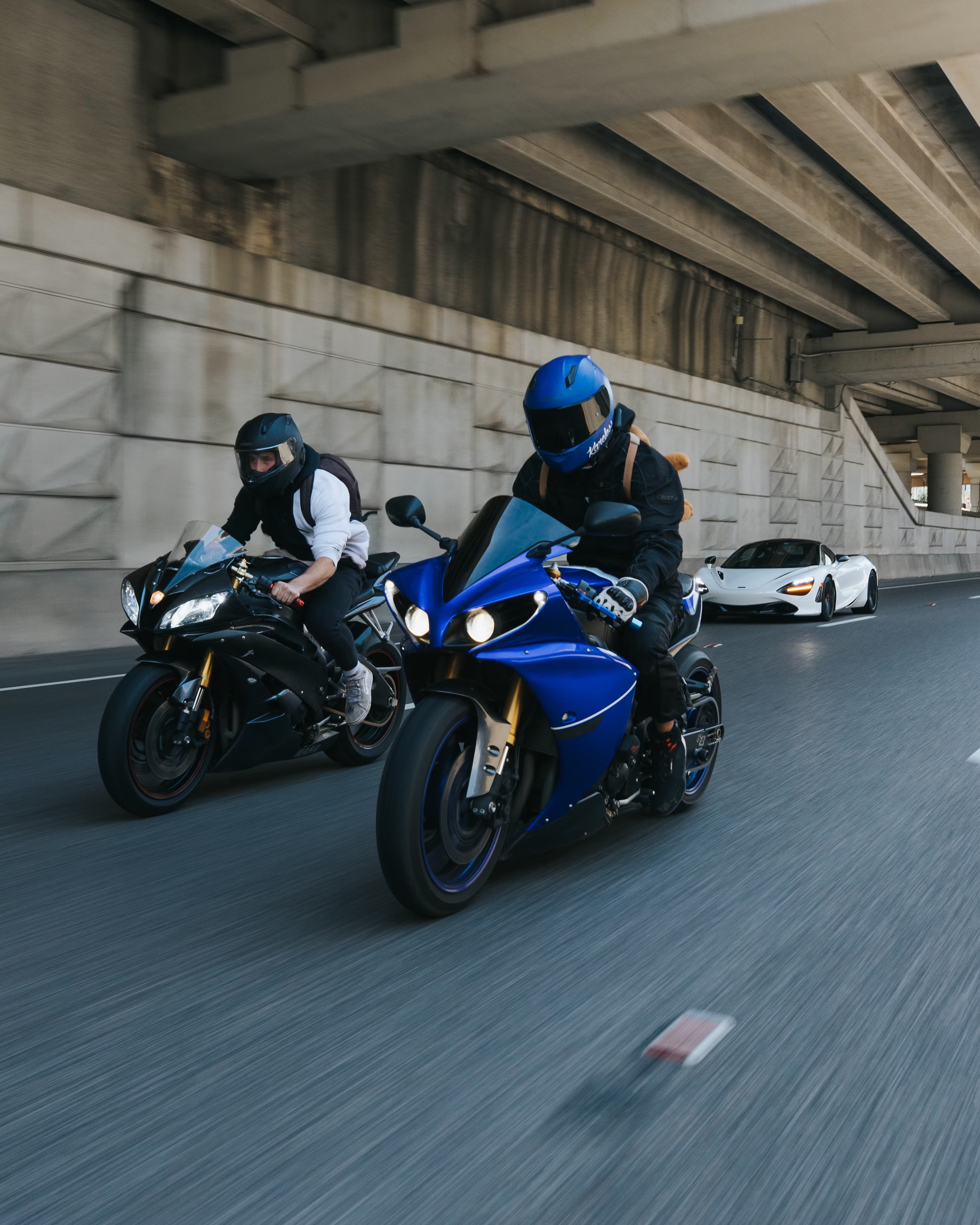 Two riders racing under a highway overpass