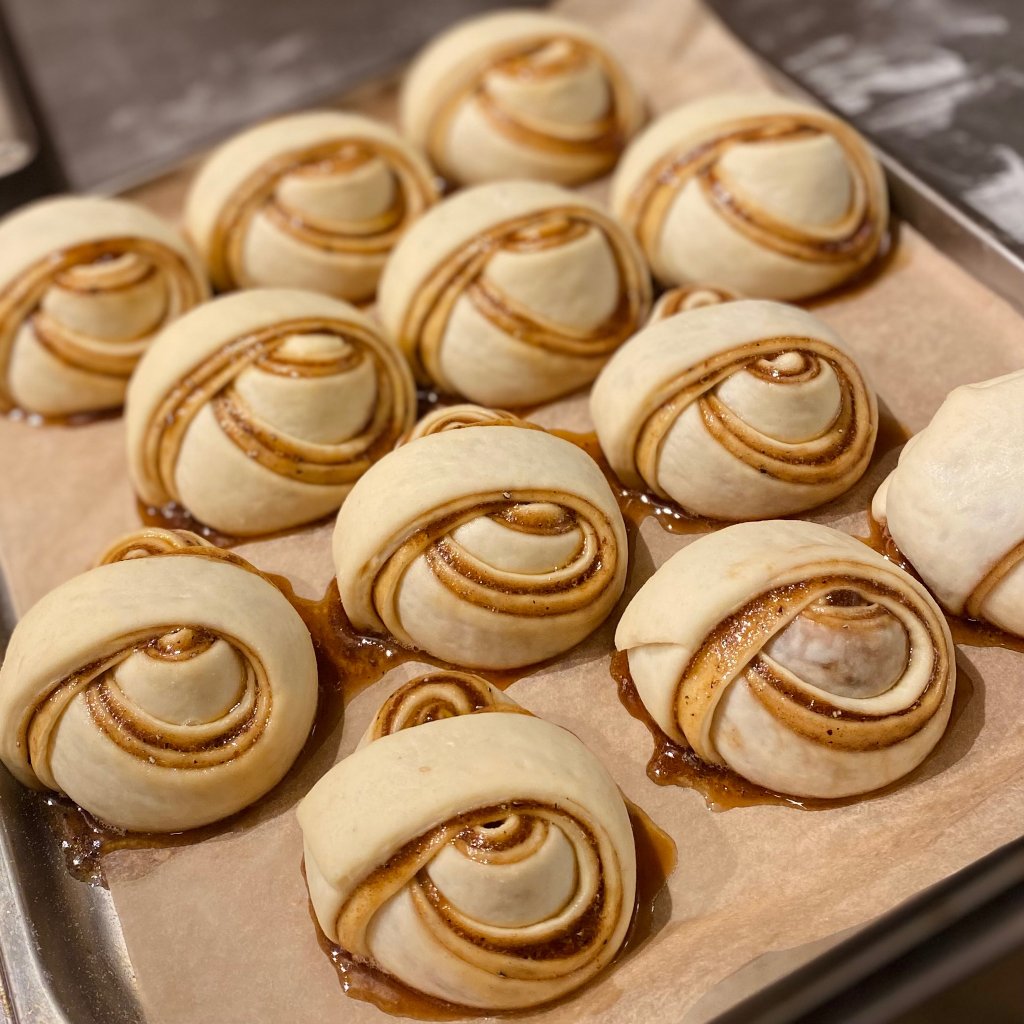 Frisch gerollte Zimtschnecken auf Backpapier bereit zum Backen