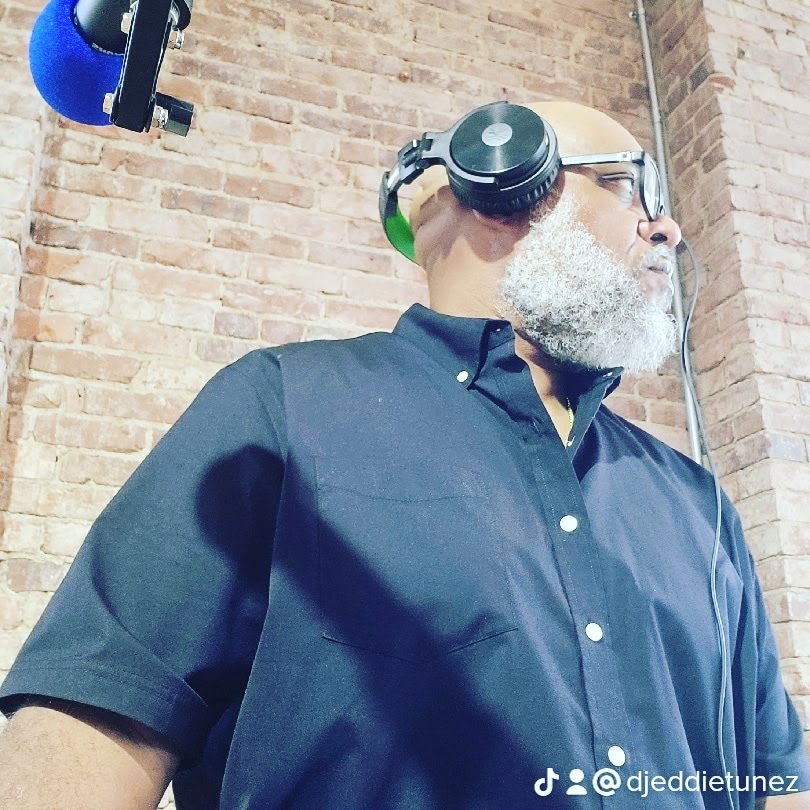 DJ Eddietunez in profile with headphones against a brick wall