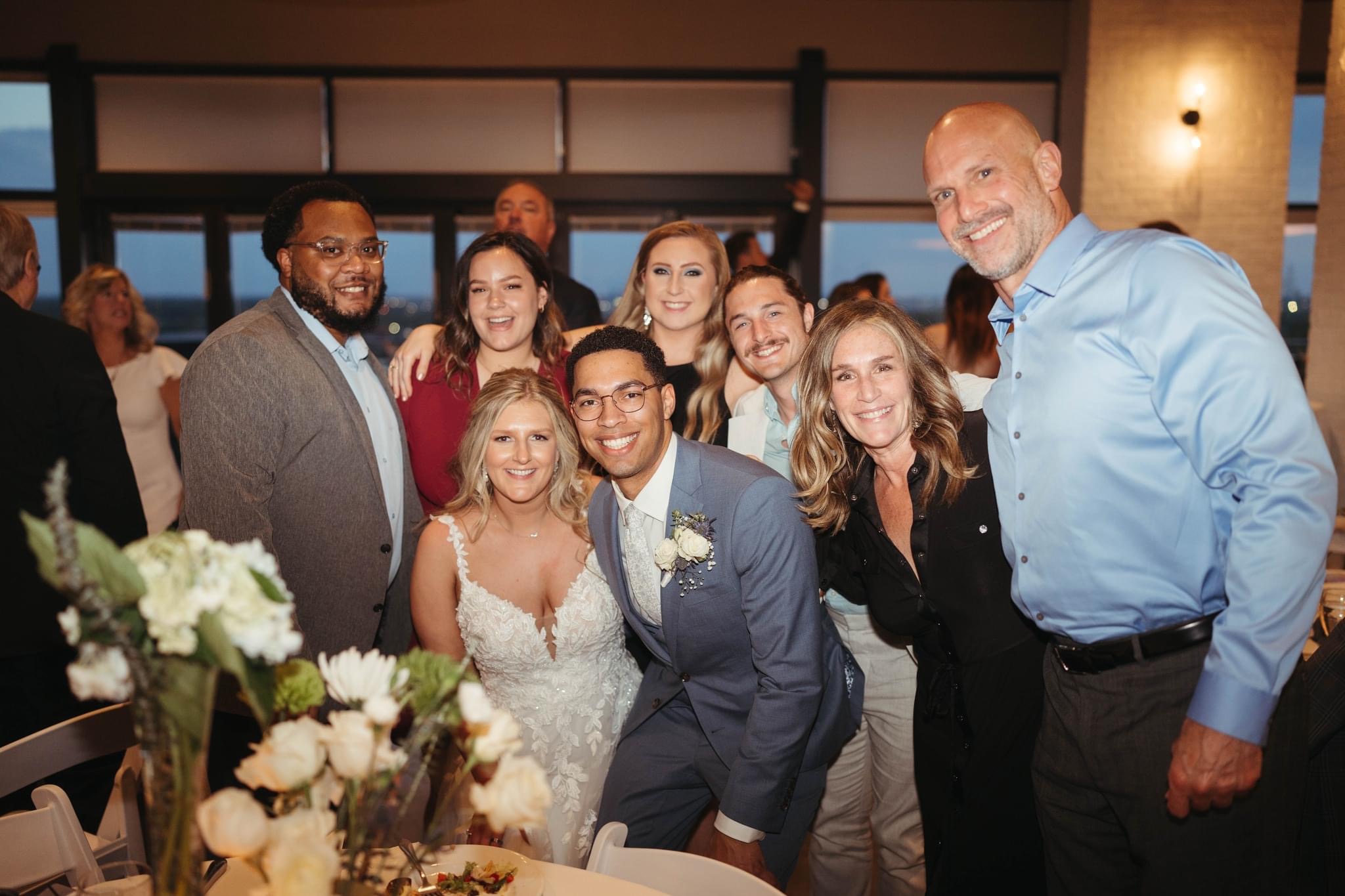 Bride, groom, and wedding party posing together at a reception