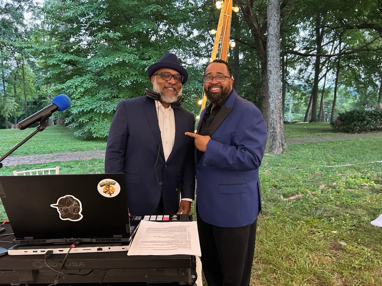 The Jones Collective DJs posing behind the booth at an outdoor event