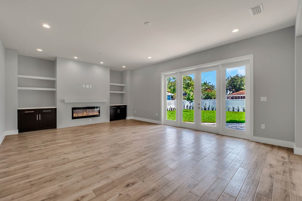 Contemporary spec home at 1332 W Yale Street, College Park, Orlando FL — gray stucco exterior with standing-seam metal roof, red double doors, glass garage, and tropical landscaping.