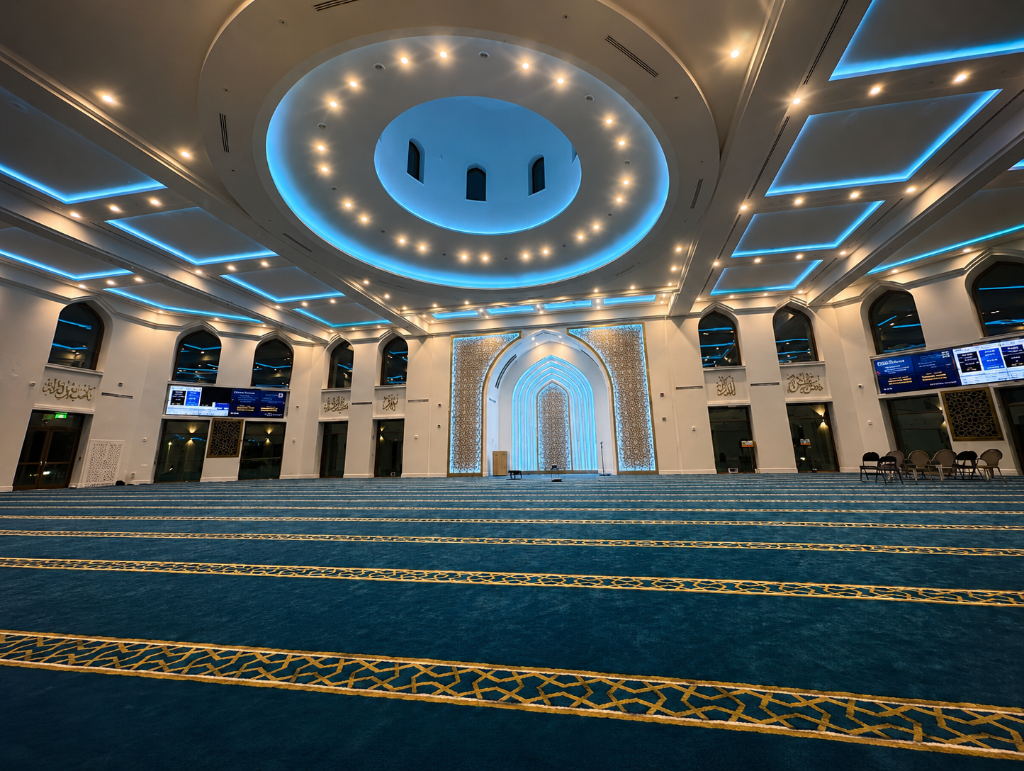 Interior of The Islamic Center of Orlando prayer hall with domed ceiling, gold mihrab, and teal prayer carpet