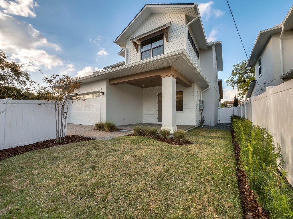 Modern farmhouse new construction with white board-and-batten exterior, metal roof, and front porch in Orlando
