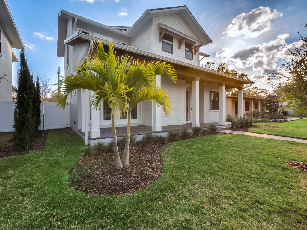 Modern farmhouse new construction with white board-and-batten exterior, metal roof, and front porch in Orlando