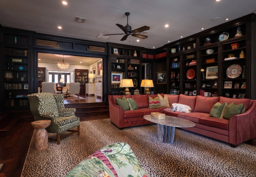 Eclectic residential interior with dark built-in bookshelves, coral sofa, leopard rug, and layered furnishings in Winter Park