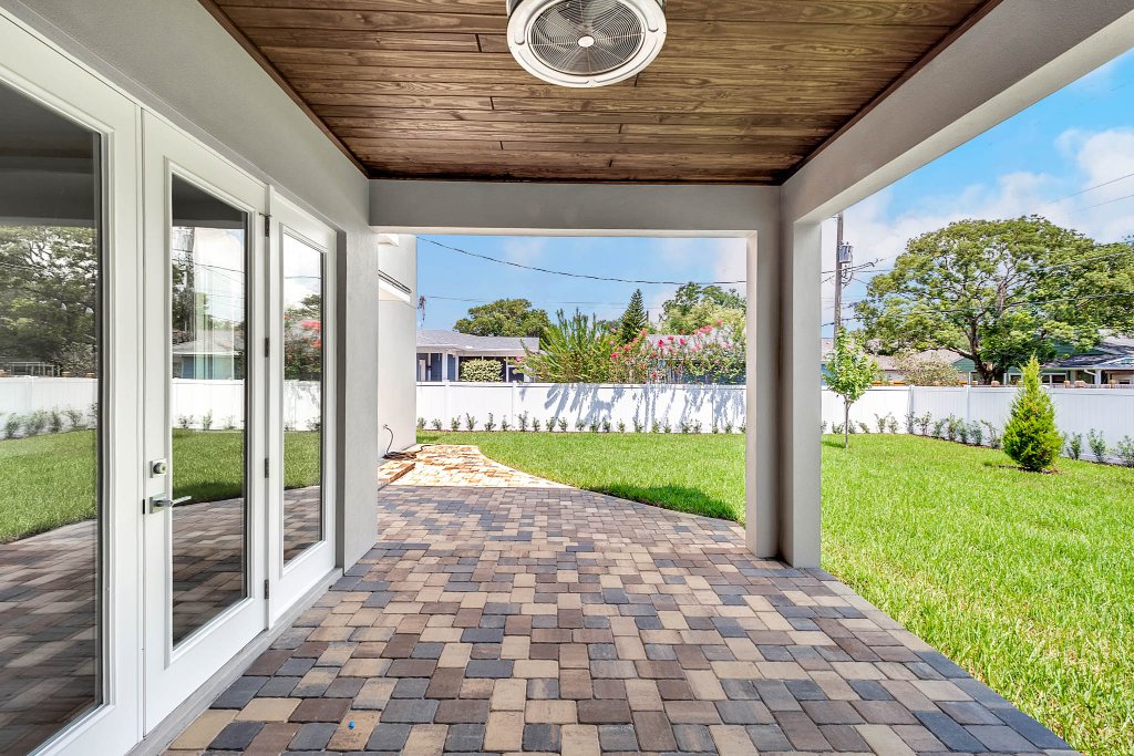 Contemporary spec home at 1332 W Yale Street, College Park, Orlando FL — gray stucco exterior with standing-seam metal roof, red double doors, glass garage, and tropical landscaping.