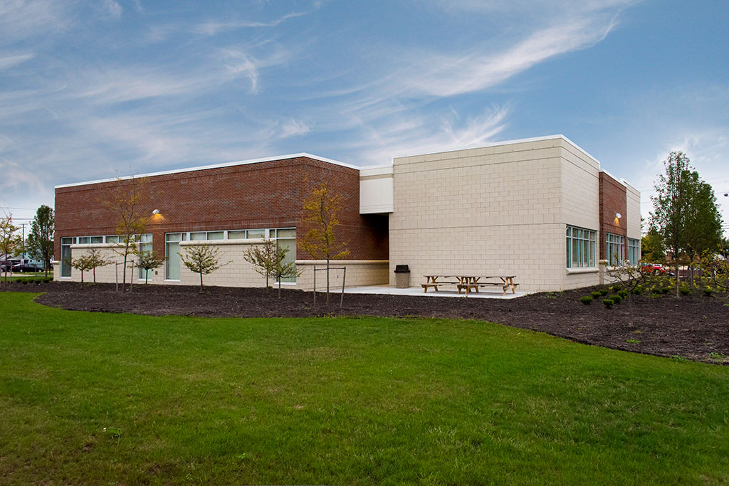 Night exterior of Stark State College Alliance Satellite Center in Alliance, OH — brick and masonry civic building with illuminated entry canopy, large glazing, and branded signage glowing against a deep blue sky