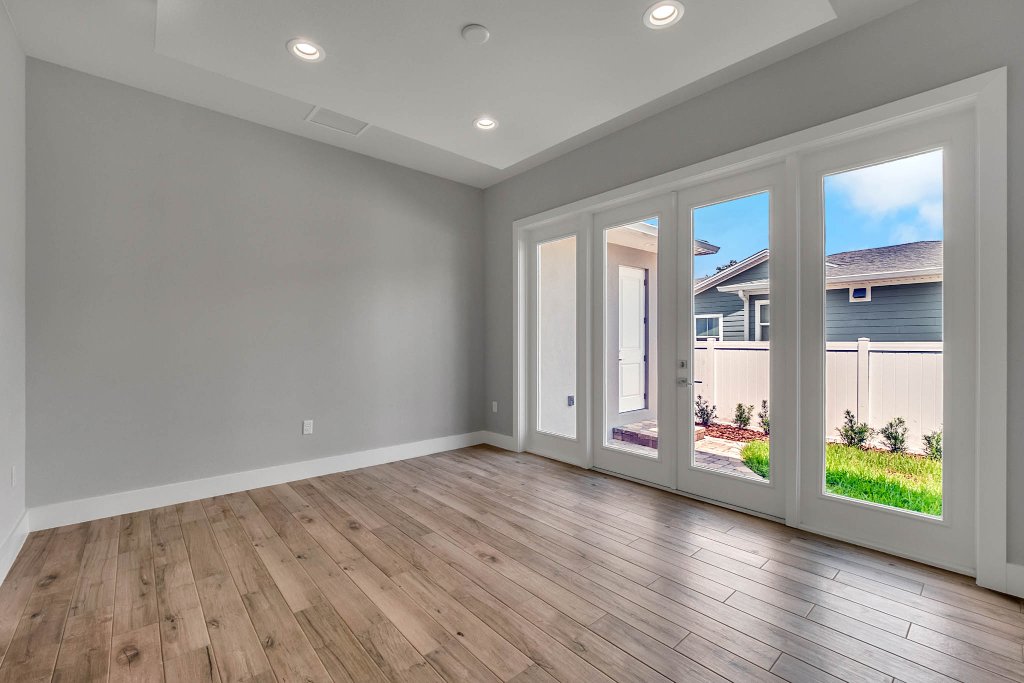 Contemporary spec home at 1332 W Yale Street, College Park, Orlando FL — gray stucco exterior with standing-seam metal roof, red double doors, glass garage, and tropical landscaping.