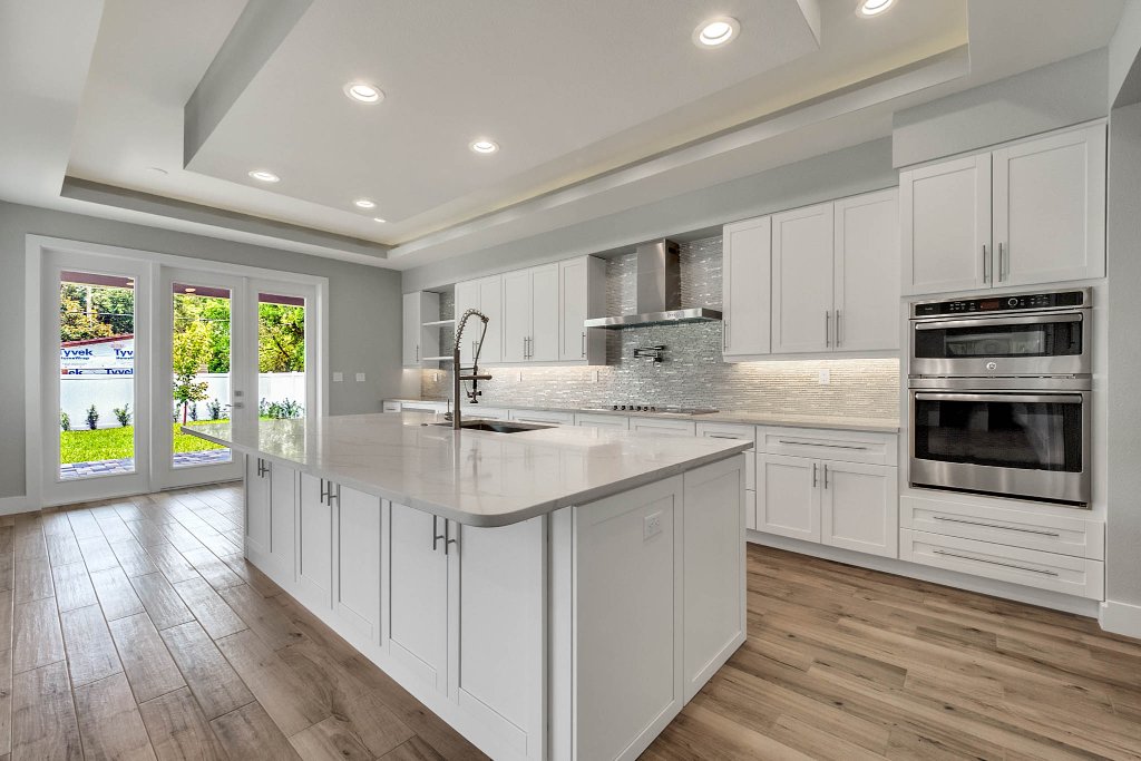 Contemporary spec home at 1332 W Yale Street, College Park, Orlando FL — gray stucco exterior with standing-seam metal roof, red double doors, glass garage, and tropical landscaping.