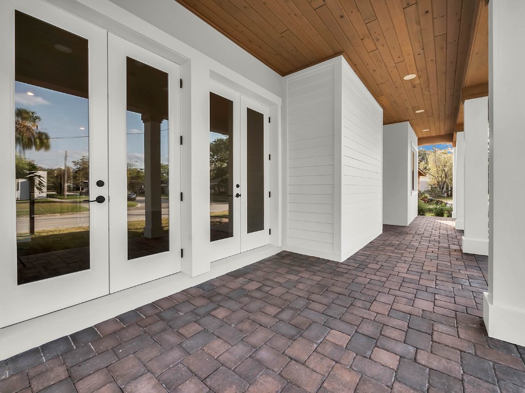 Modern farmhouse new construction with white board-and-batten exterior, metal roof, and front porch in Orlando