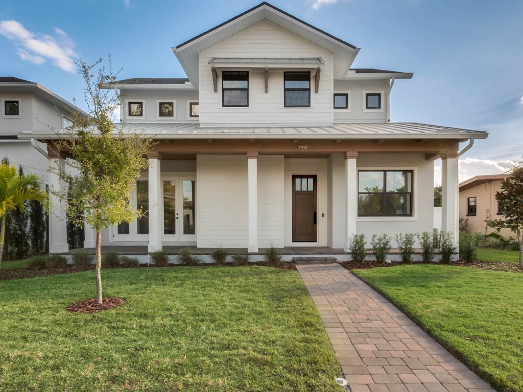 Modern farmhouse new construction with white board-and-batten exterior, metal roof, and front porch in Orlando