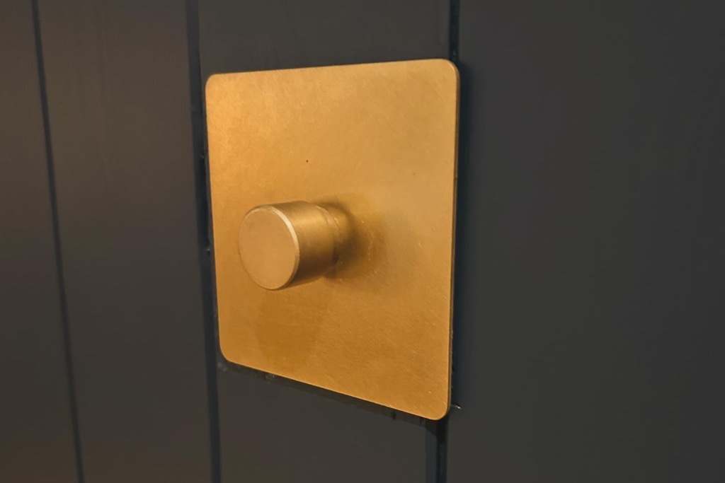 Corston Architectural Detail brass dimmer switch against blue décor