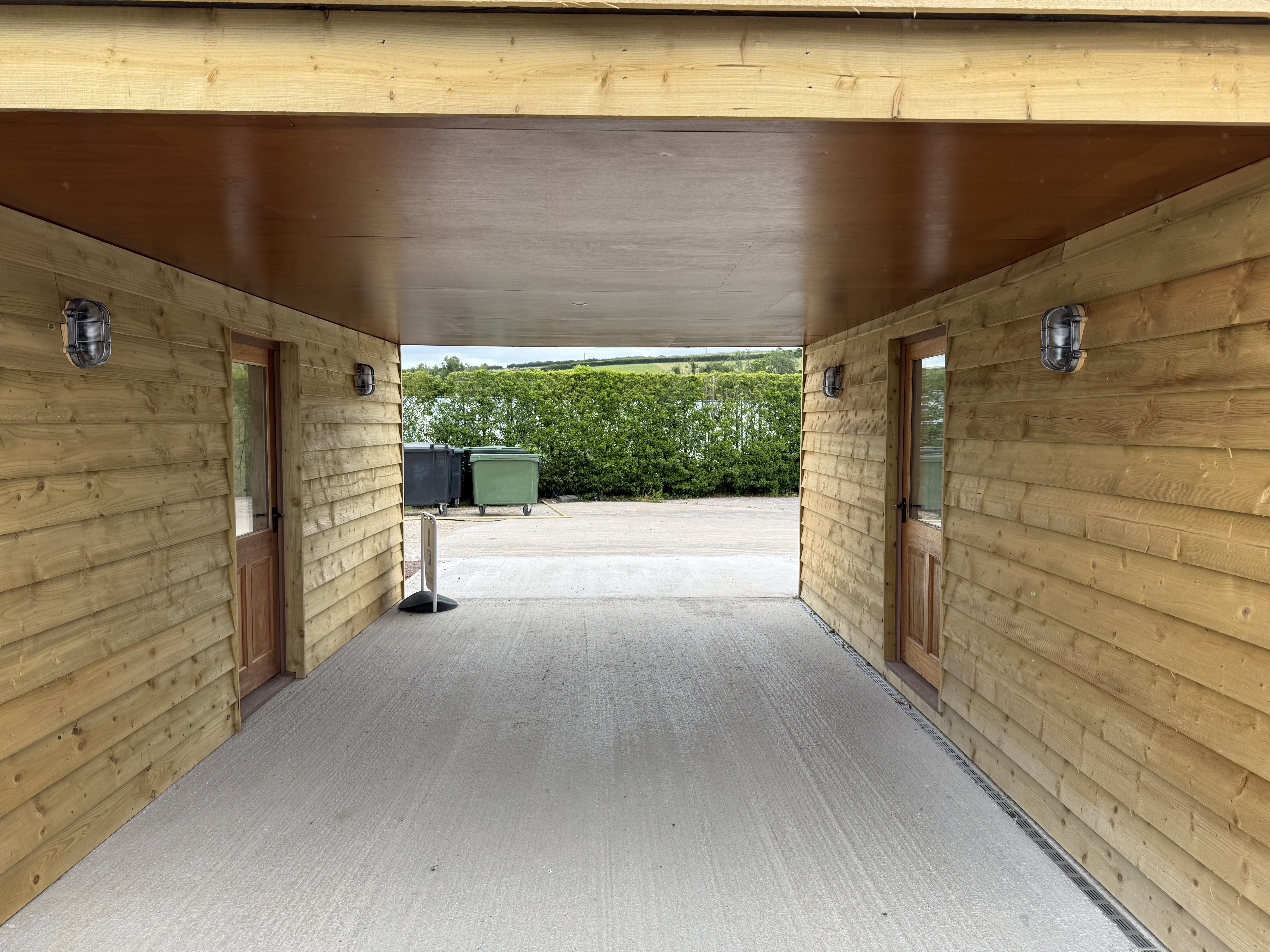 Covered breezeway - industrial cage wall sconces on timber cladding