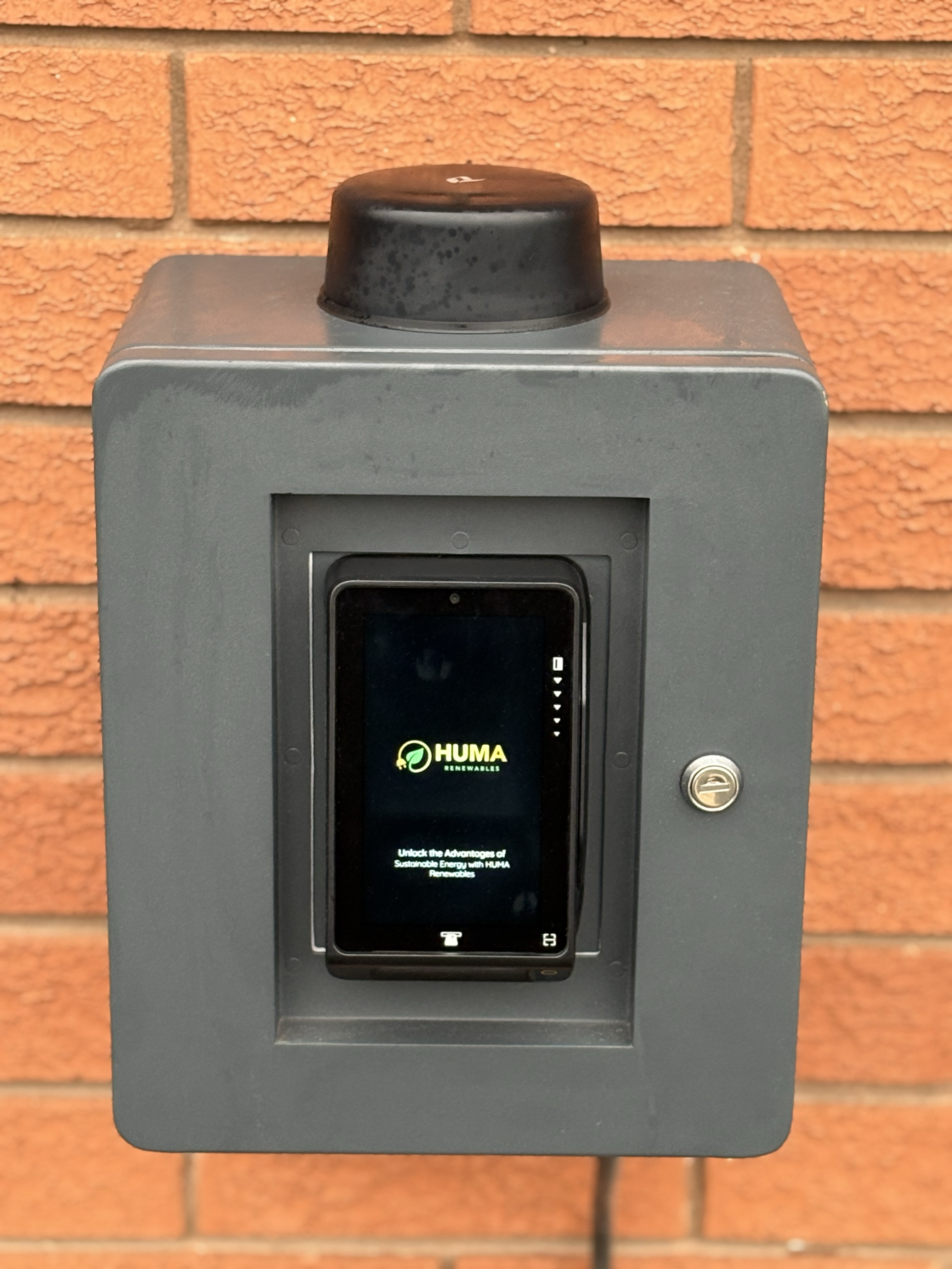 The central HUMA terminal, a grey wall-mounted control box with an active digital display showing the HUMA Renewables logo