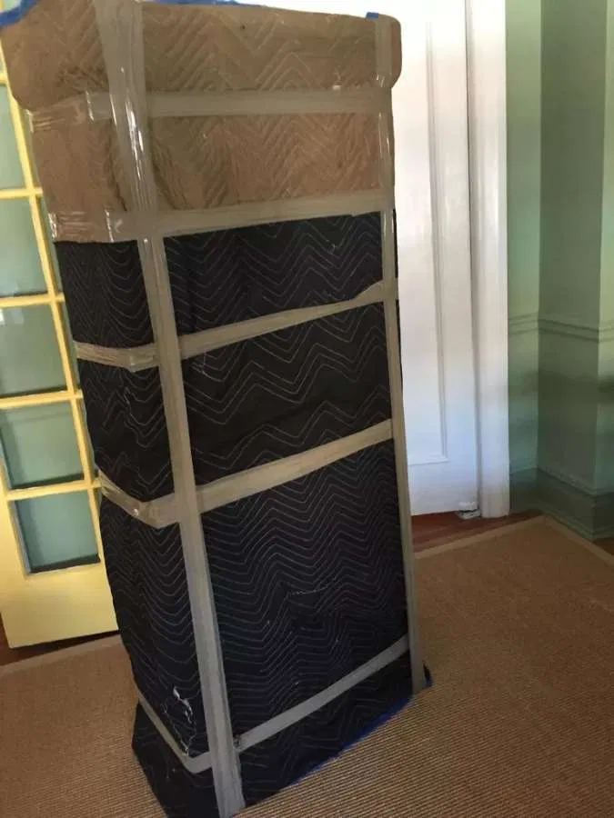 Tall armoire blanketed & taped for transit