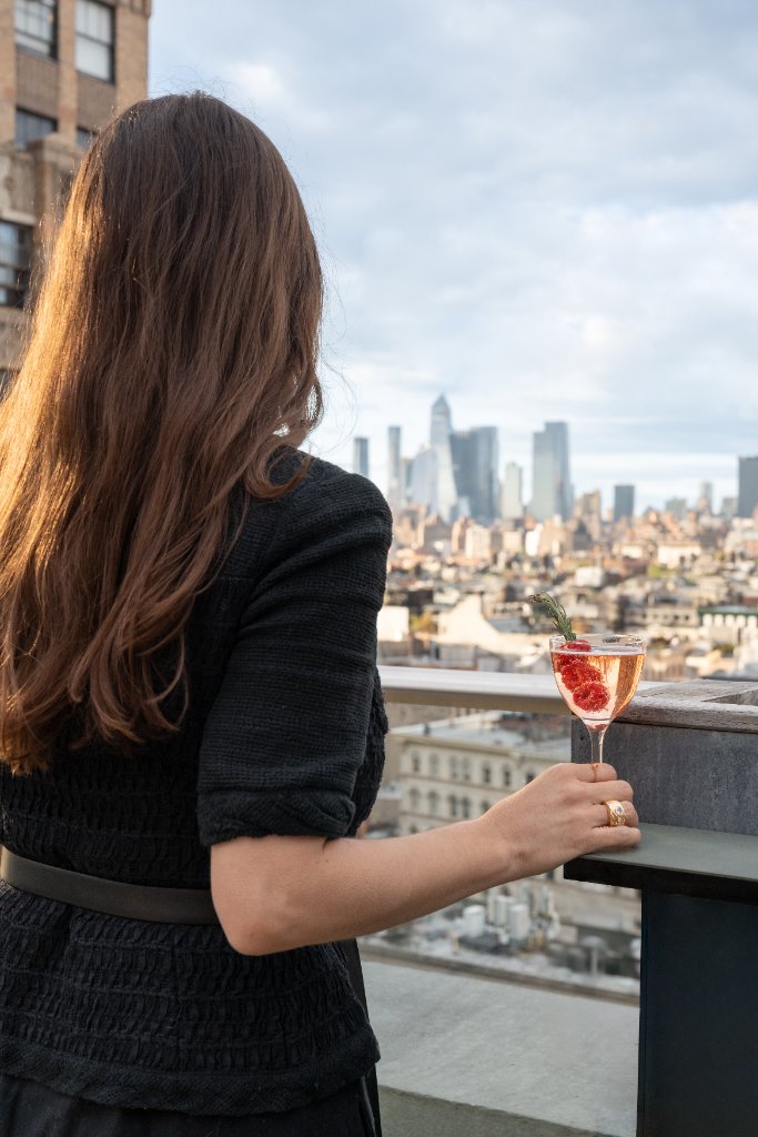 Woman with cocktail overlooking NYC skyline Walker Rooftop
