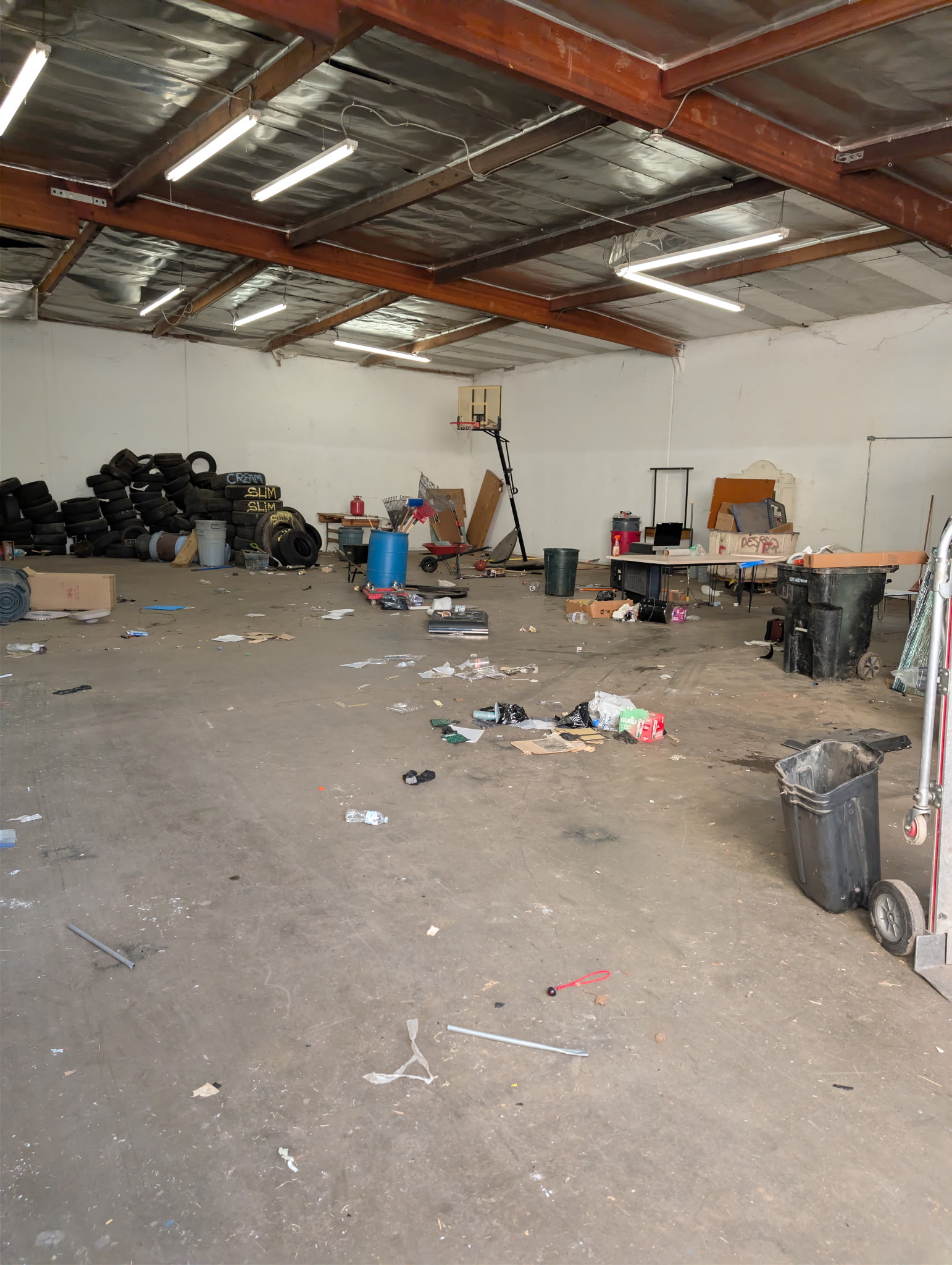 Large warehouse interior filled with tires, barrels, and debris during a commercial cleanout