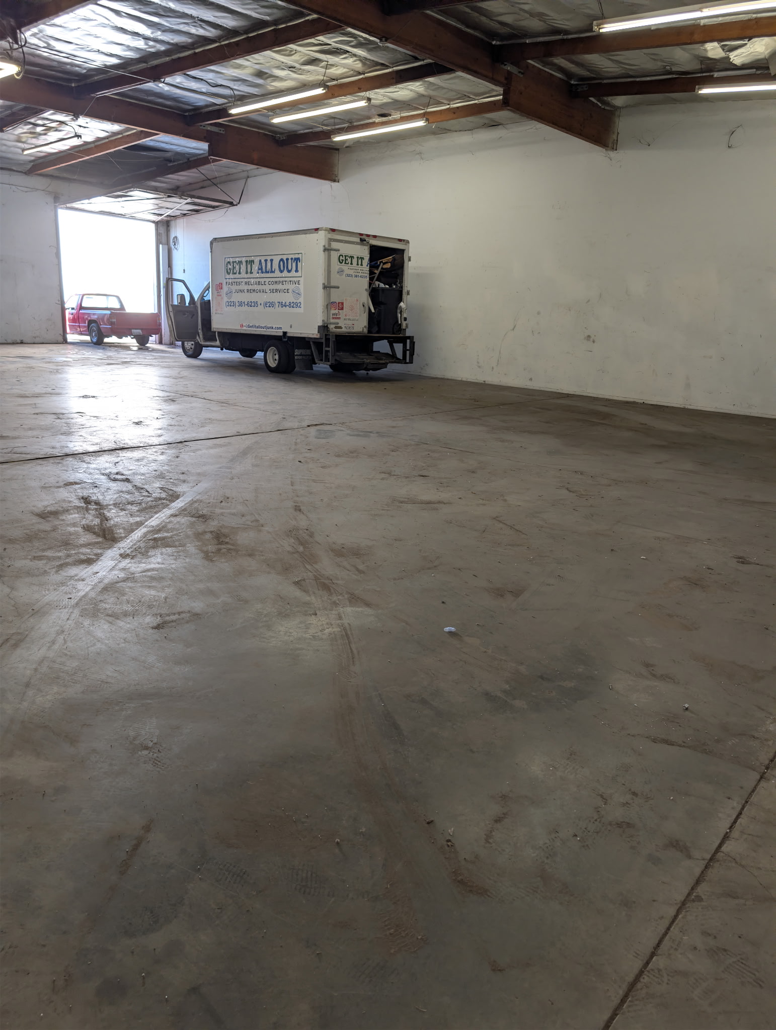 Branded Get It All Out junk removal truck inside a large industrial warehouse cleanout