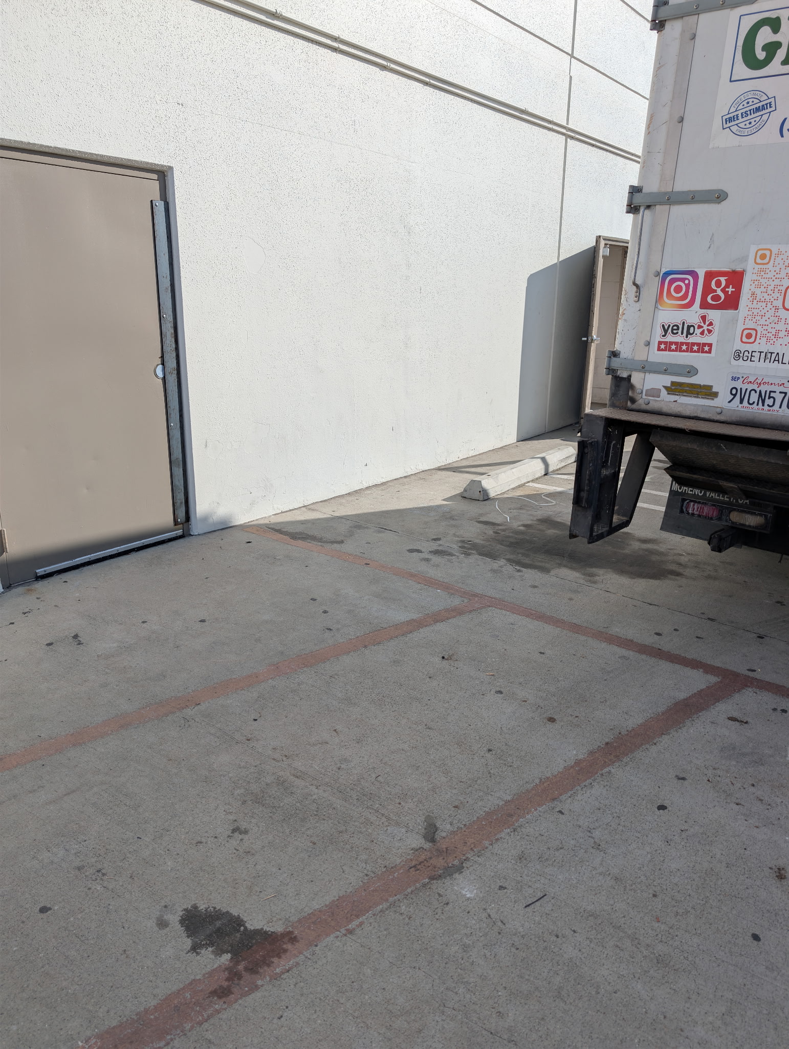 Get It All Out branded white junk removal box truck parked at a loading dock in Moreno Valley, CA