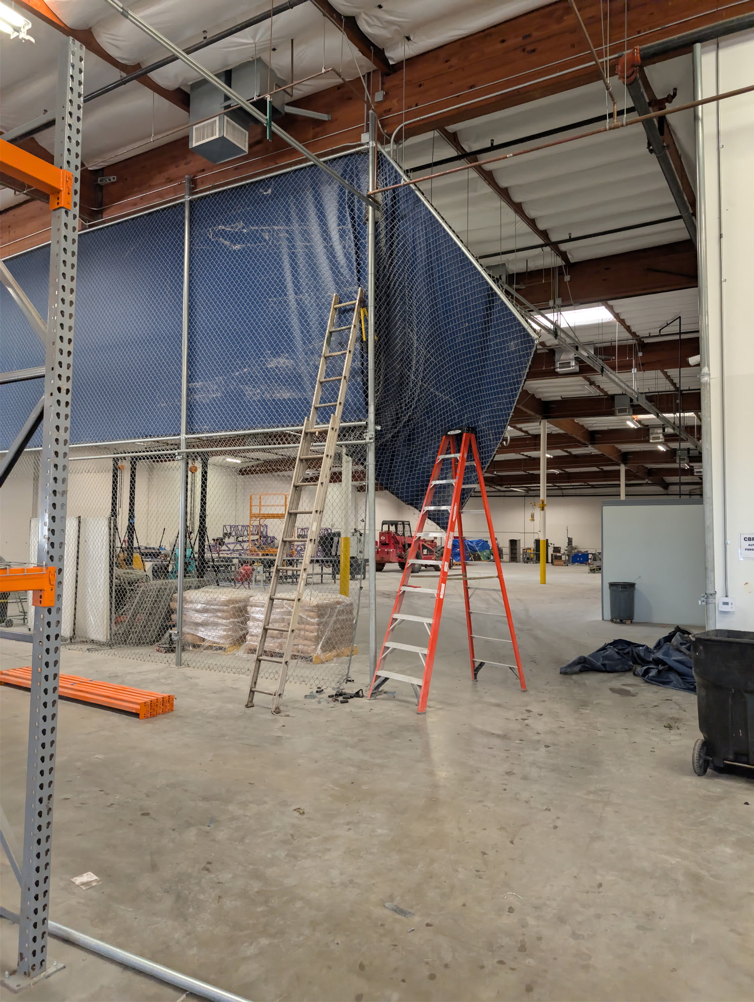 Warehouse storage area with industrial racking, ladders, and equipment staged for removal