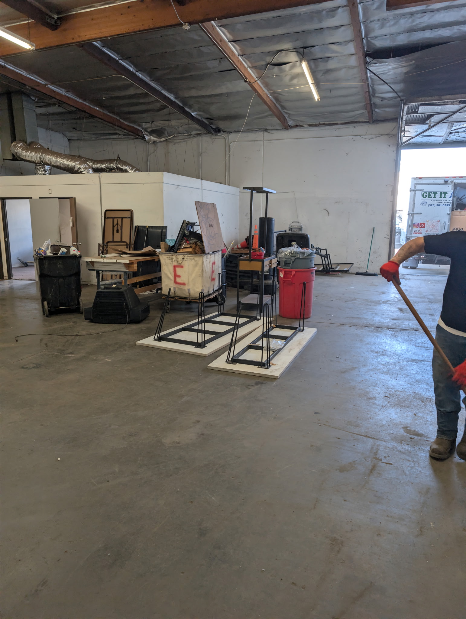 Crew member sweeping and clearing warehouse clutter during a junk removal job