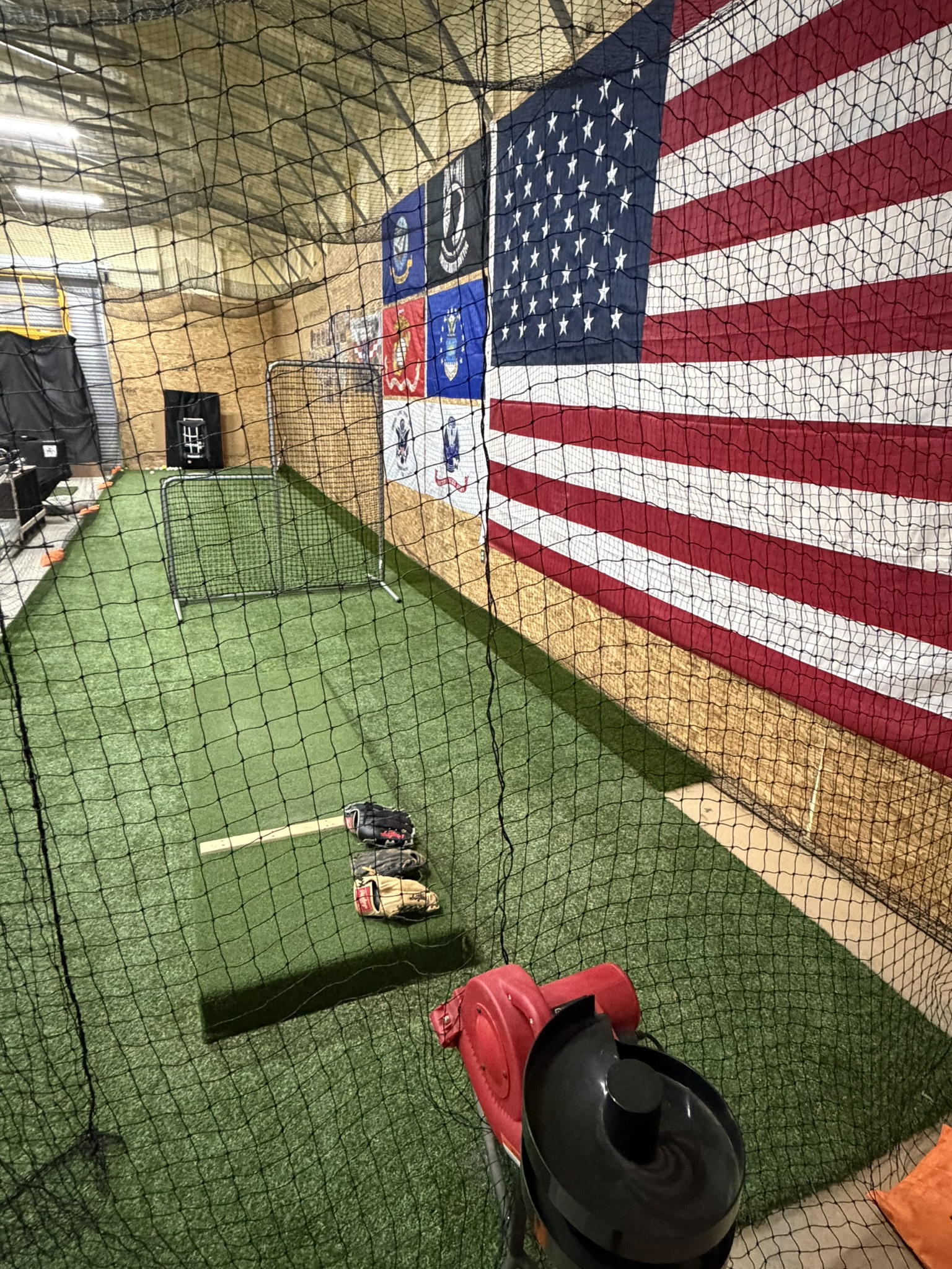 Batting practice area with turf, gloves, and netting