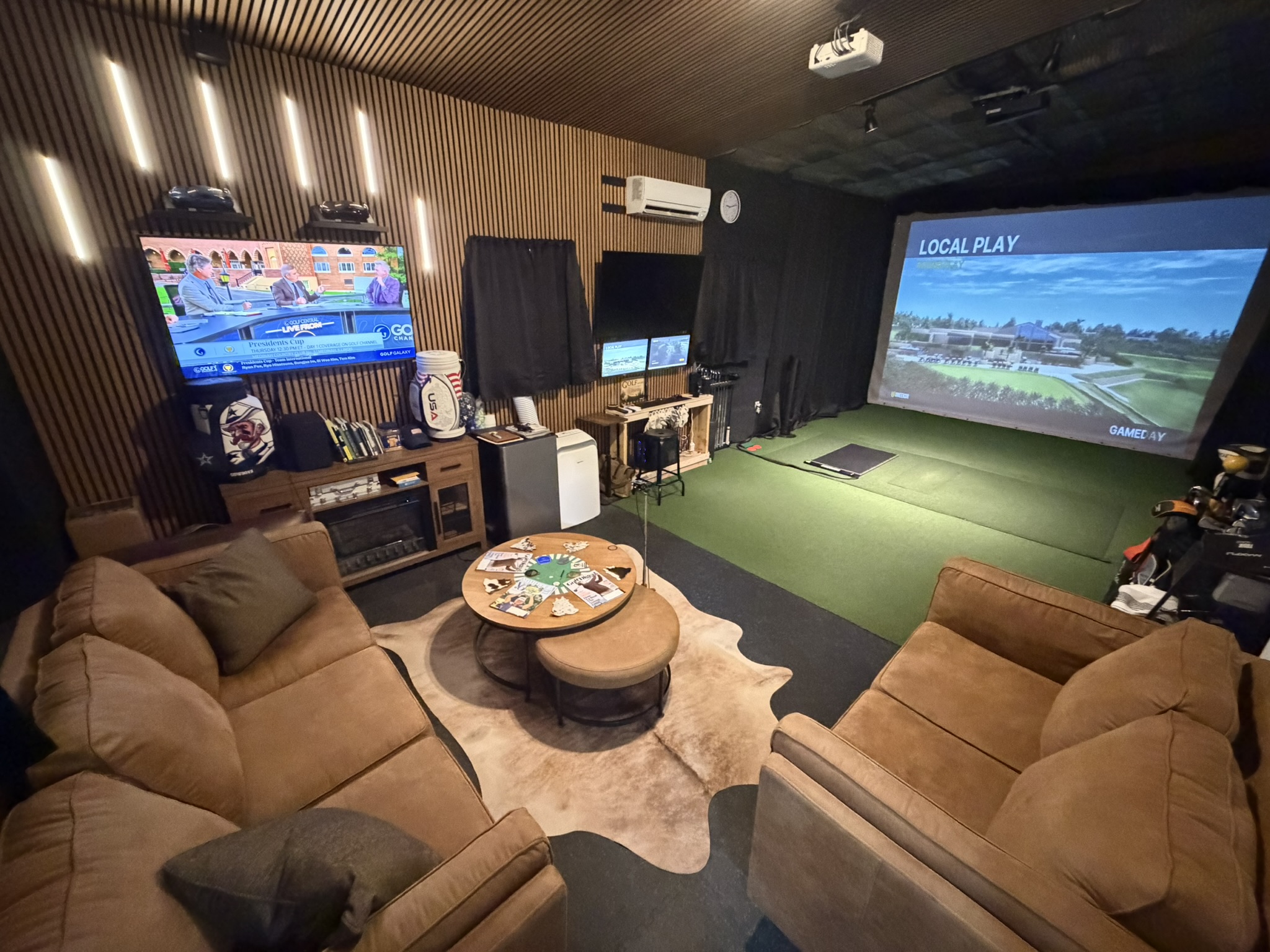 Simulator lounge with sofas, turf, and projection screen at the Powhatan location