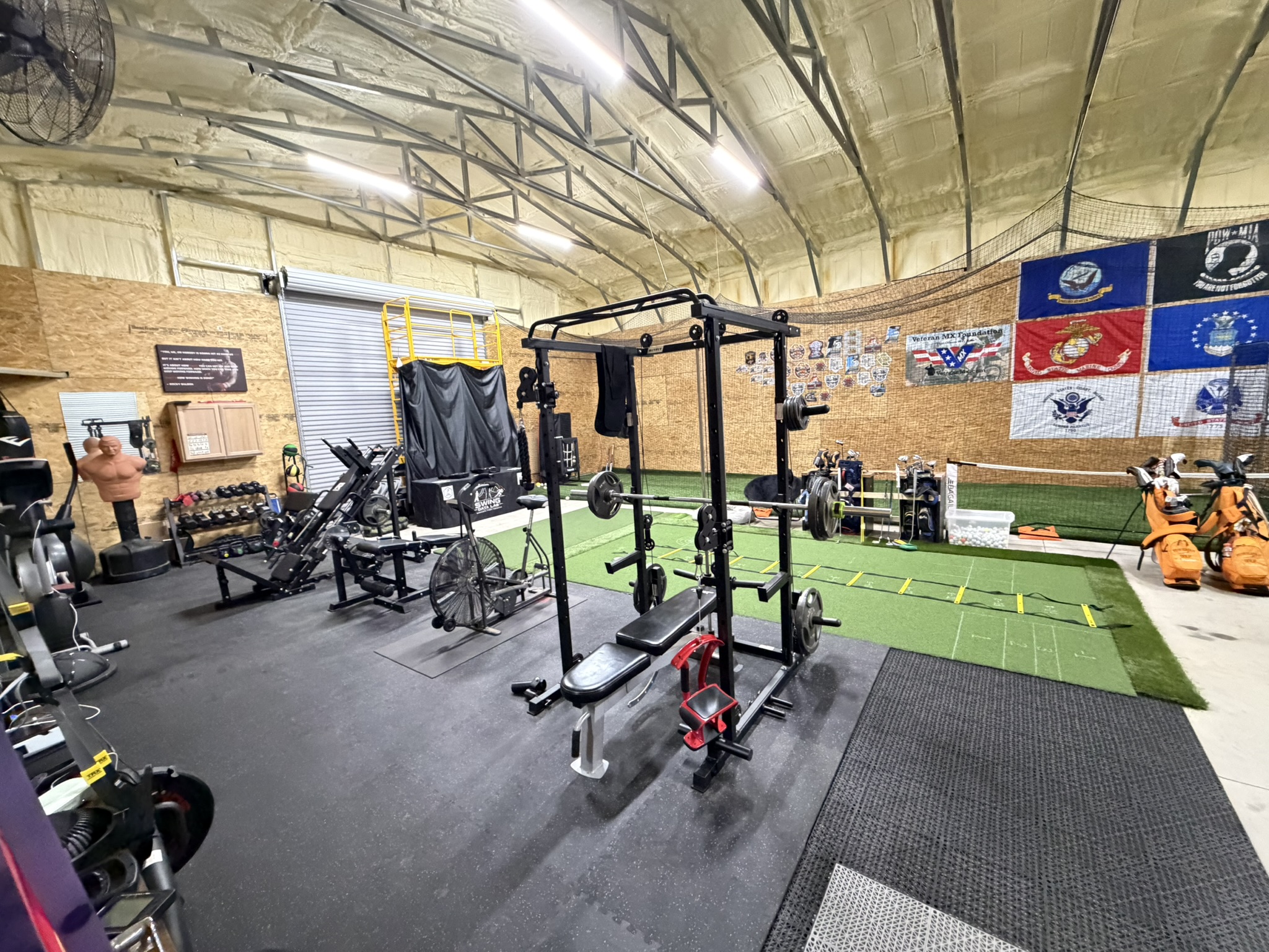 Gym area with power rack, turf strip, and flag wall