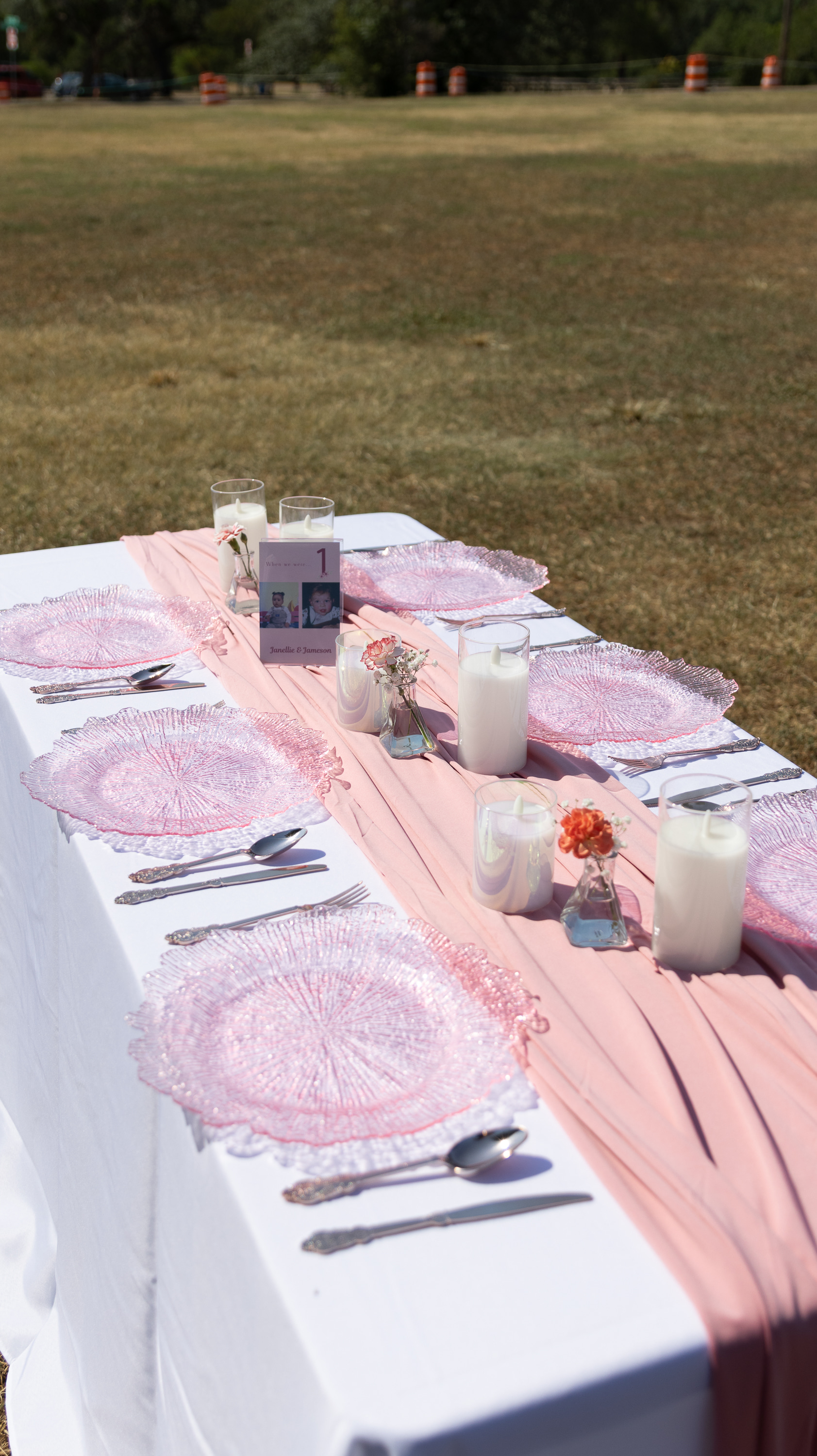 Styled outdoor celebration table with pink linens, candles, and place settings