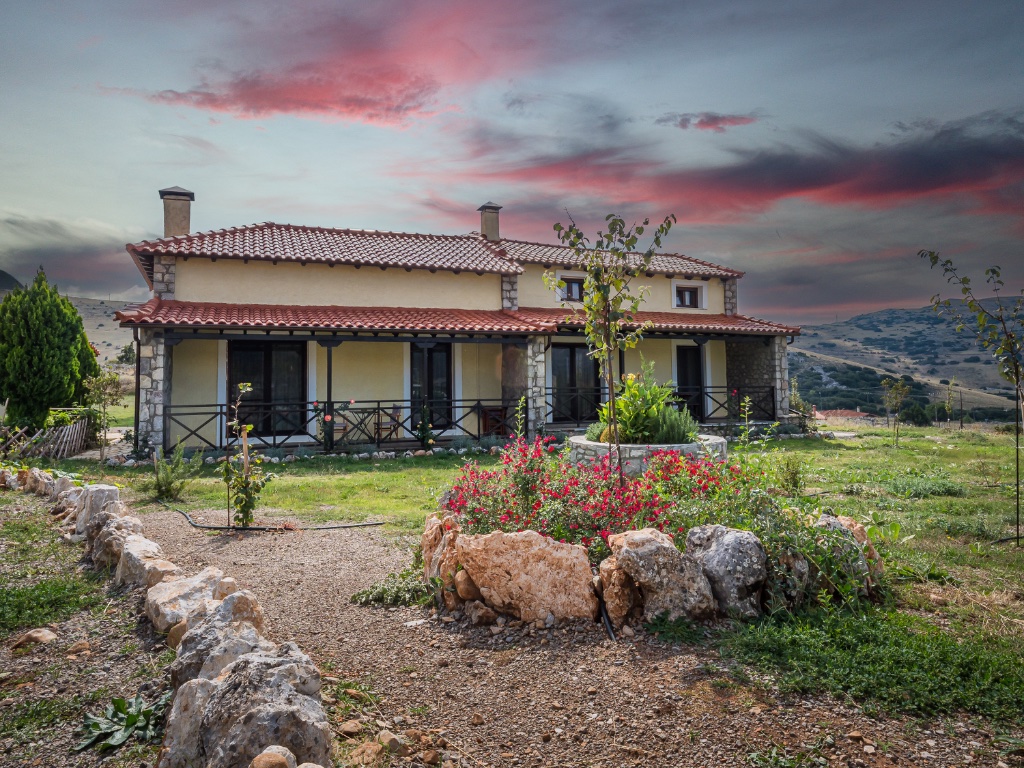 Chalet Renata 2 stone facade with summer garden under dramatic sky